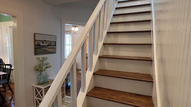 A staircase with wooden steps and white railings, leading to a second floor. - Restored 2-bedroom cottage in beautiful California, MO (California)