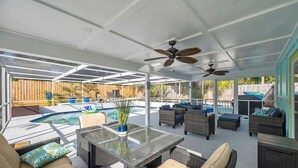 Un espacio al aire libre cubierto con piscina, muebles de mimbre y ventiladores de techo.