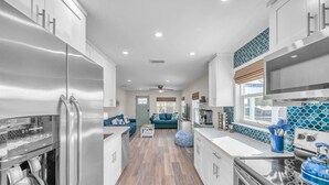 Una cocina moderna con electrodomésticos de acero inoxidable, una isla central y vistas a una sala de estar.