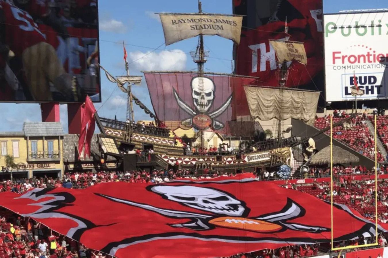 A stadium with a large pirate-themed flag and a skull emblem, surrounded by spectators.