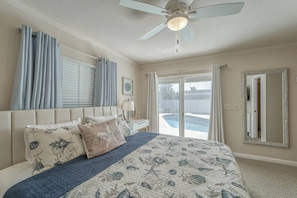 A bedroom with a bed, a ceiling fan, a window with curtains, and a view of a swimming pool. - Coastal Iris - near Gulf beaches, trail, shoppong (Seminole)
