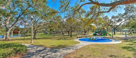Un parque con un parque infantil, un estanque y un pabellón.