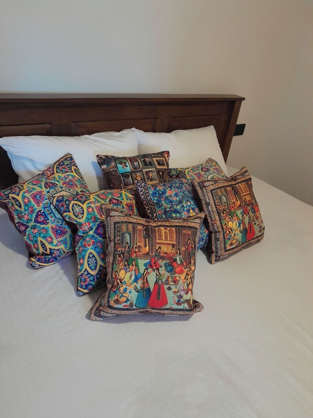 A bed with multiple colorful pillows and a wooden headboard.