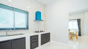 Una cocina moderna con estufa integrada, un lavamanos y una ventana con persianas.
