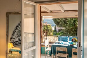 An open balcony with a table set for dining, a chair, and a lamp. - Tiffany With Shared Pool, Marinella, Italy (Marinella)