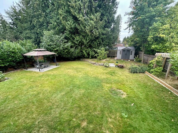 Un jardin avec une table de patio, un abri de jardin et un espace potager.