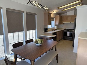 A modern kitchen with wooden cabinets, a dining table with chairs, a built-in oven, and a coffee maker. - Cienega Springs Getaway (Parker)