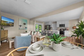 Una sala moderna con un sofá, una mesa de comedor y una cocina al fondo.