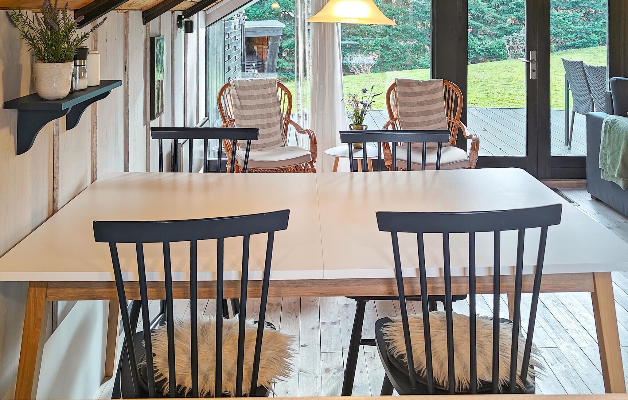 Un coin repas avec une table et des chaises en bois, une plante en pot et une vue sur l’extérieur.