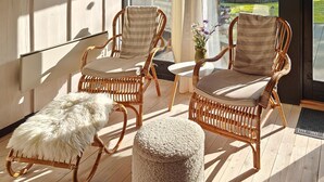 A room with wicker chairs, a fluffy white ottoman, and a view through a glass door. - Gorgeous home in Ansager with WiFi (Ansager)