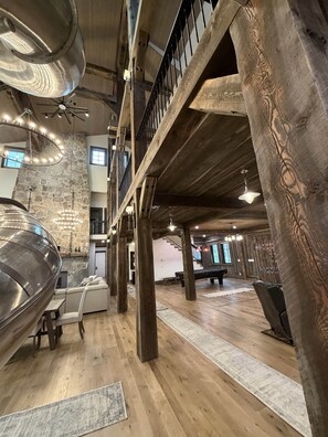 A spacious interior with a high ceiling, wooden beams, stone walls, and a mezzanine level. - Yellowstone Adventure Lodge (Fremont County)