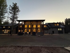 A large, multi-story building with a prominent wooden structure in the center, surrounded by a gravel driveway and trees. - Yellowstone Adventure Lodge (Fremont County)
