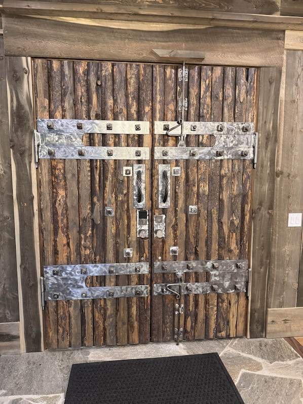 A rustic wooden door with metal hardware and a black doormat. - Yellowstone Adventure Lodge (Fremont County)