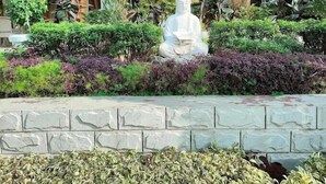 A statue of a seated figure surrounded by a variety of plants and shrubs. - HOTEL PALLAVI GRAND (Panchkula)