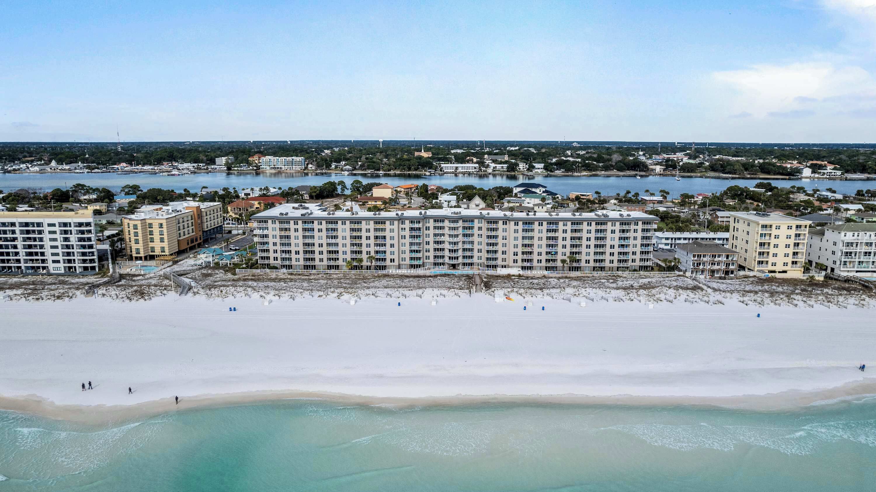 A beachfront hotel with multiple buildings, a sandy beach, and a clear view of the ocean.