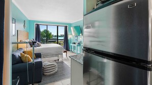Une chambre moderne équipée d’un lit, d’un canapé, d’un coin cuisine avec réfrigérateur et offrant une vue sur l’extérieur.