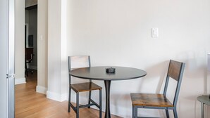 Una pequeña mesa redonda con dos sillas, una puerta que da a otra habitación e interruptor de luz en la pared.