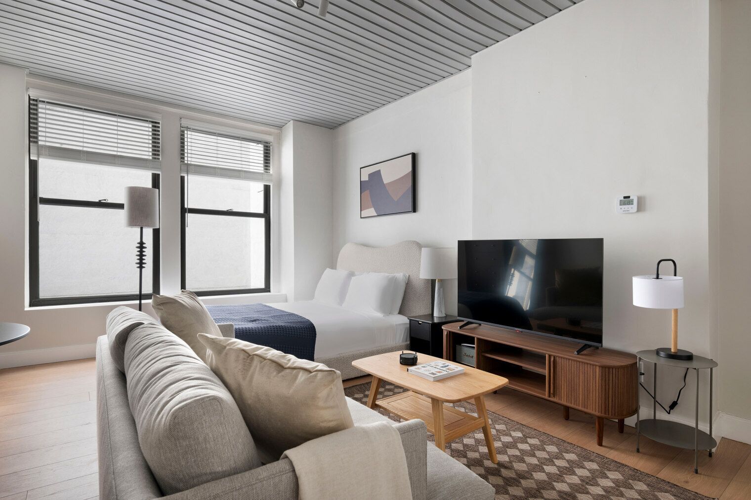 Une chambre d’hôtel moderne équipée d’un canapé, d’une télévision, d’une petite table et d’une lampe.