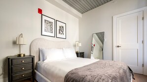 Ein Schlafzimmer mit einem Bett, Nachttischen, einem Spiegel und zwei gerahmten Bildern an der Wand.