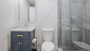 Een moderne badkamer met een wit wastafelmeubel, toilet en een douchecabine met glazen wanden.