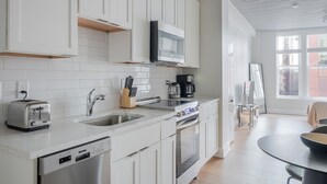 Een moderne keuken met witte kasten, een roestvrijstalen spoelbak, een broodrooster, een koffiezetapparaat en een vaatwasser.