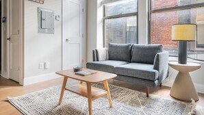 Ein modernes Wohnzimmer mit einem grauen Sofa, einem kleinen Holztisch und einer Lampe.