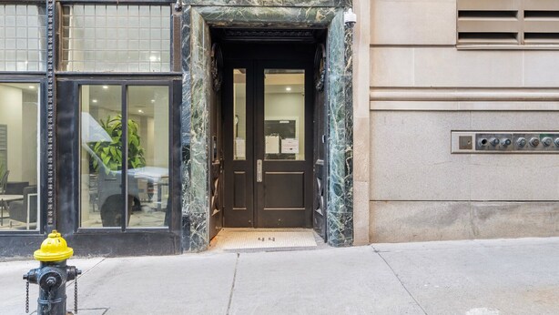 A building entrance with a marble facade, a black door, and a fire hydrant on the sidewalk. - Blueground | Downtown Crossing, view, nr Boston Common (Boston)