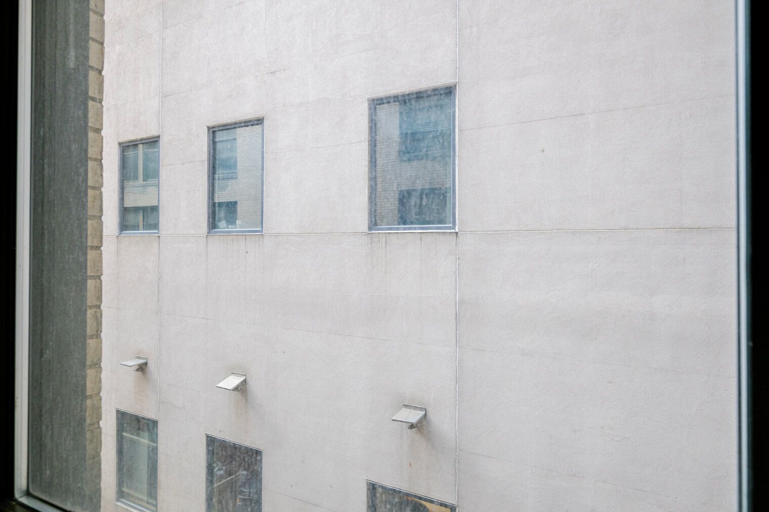 A building facade with multiple windows and a brick section on the left.
