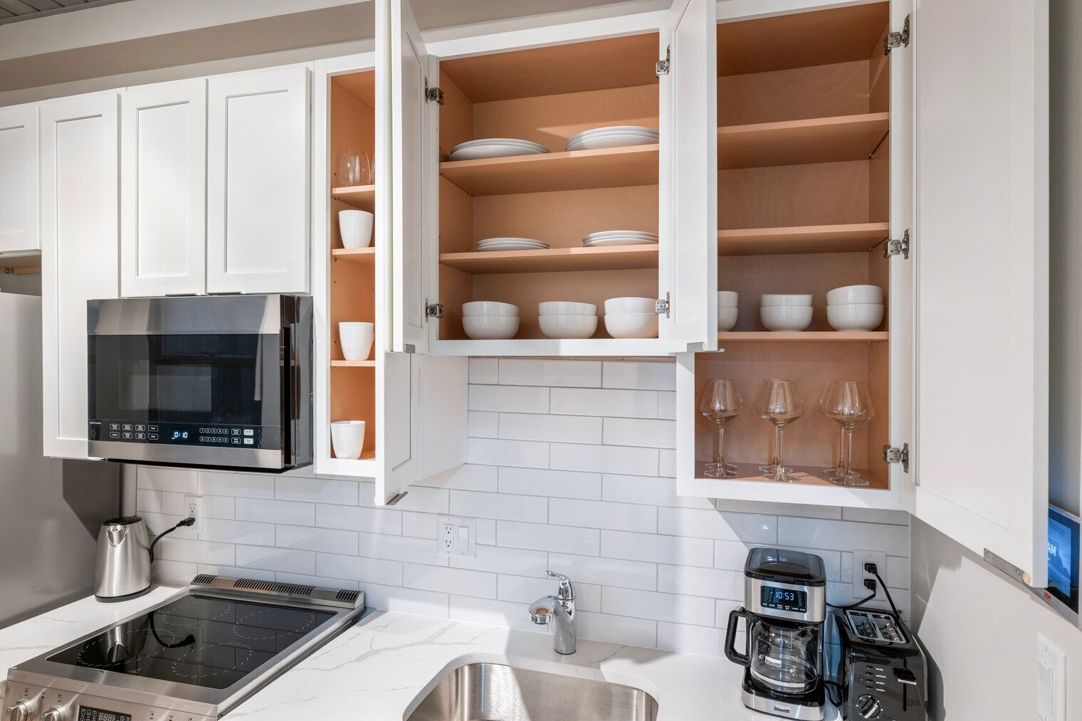 A modern kitchen with white cabinets, a microwave, a coffee maker, and a toaster.