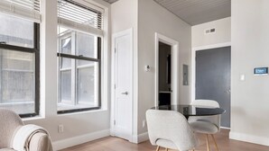 Een moderne woonkamer met een ronde glazen tafel, twee grijze stoelen en een beige bank.
