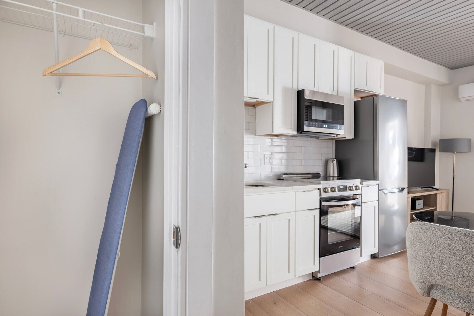A modern kitchen with white cabinets, a stainless steel refrigerator, a microwave, and a stove.