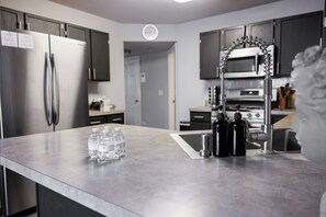 A modern kitchen with stainless steel appliances, a marble countertop, and a water dispenser. - Peaceful 3-Bedroom Townhome in Crest Hill /Queen Beds, Full Amenities & Gazebo (Crest Hill)