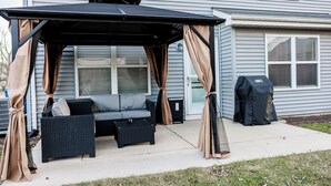 A covered patio with a sofa and cushions, a grill, and a pergola with curtains. - Peaceful 3-Bedroom Townhome in Crest Hill /Queen Beds, Full Amenities & Gazebo (Crest Hill)