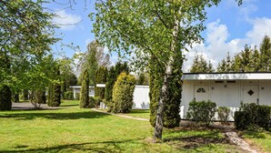 A row of white cabins with numbered doors, surrounded by well-maintained lawns and trees. - Amazing home in Ystad with WiFi (Ystad)