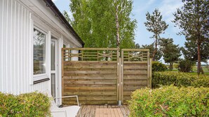Une porte en bois, un bâtiment blanc et une terrasse en bois avec une chaise.