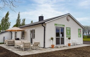 A white building with a reception desk, outdoor seating, and a sign for 'RECEPTION & BUTIK.' - Beautiful home in Ystad (Ystad)