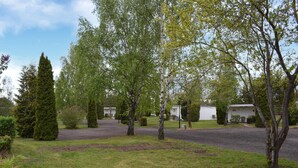 A residential area with a paved driveway, a white building, and various trees. - Gorgeous home in Ystad (Ystad)