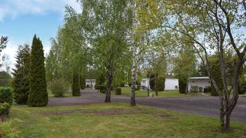 Ett bostadsområde med en asfalterad uppfart, en vit byggnad och olika sorters träd.