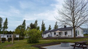 A white building with a patio area, surrounded by trees and a grassy lawn. - Gorgeous home in Ystad (Ystad)
