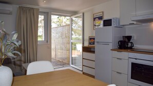 Cocina compacta con comedor, refrigerador, microondas, cafetera y puerta corrediza de vidrio que da a un espacio exterior.