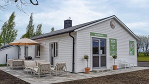 A white building with a reception desk, outdoor seating, and potted plants. - Amazing home in Ystad with house a panoramic view (Ystad)
