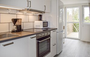 A modern kitchen with a coffee maker, microwave, oven, and a sliding glass door leading to a balcony. - 1 bedroom lovely home in Ystad (Ystad)