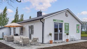 En vit byggnad med en receptionsdisk, utomhusplatser och en skylt med texten ”RECEPTION & BUTIK”.