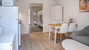 A compact living space with a kitchenette, a dining area with a table and chairs, a sofa, and a bunk bed in the background. - Beautiful home in Ystad (Ystad)