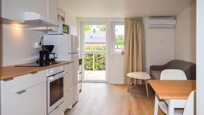 A compact kitchen with a coffee maker, microwave, and oven. There's a dining area with a table and chairs, and a sliding glass door leading to a balcony. - Beautiful home in Ystad (Ystad)