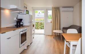A compact kitchen with a coffee maker, microwave, and oven. There's a dining area with a table and chairs, and a sliding glass door leading to a balcony. - Beautiful home in Ystad (Ystad)