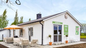 A white building with a reception desk, outdoor seating, and a sign indicating 'RECEPTION & BUTIK.' - Beautiful home in Ystad (Ystad)