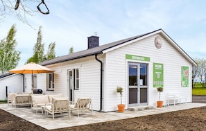 A white building with a reception desk, outdoor seating, and a sign indicating 'RECEPTION & BUTIK.' - Beautiful home in Ystad (Ystad)
