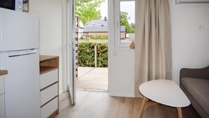 A compact kitchen with a refrigerator, a wooden cabinet, a small table, and a window with curtains. - Beautiful home in Ystad (Ystad)