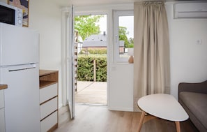 A compact kitchen with a refrigerator, a wooden cabinet, a small table, and a window with curtains. - Beautiful home in Ystad (Ystad)